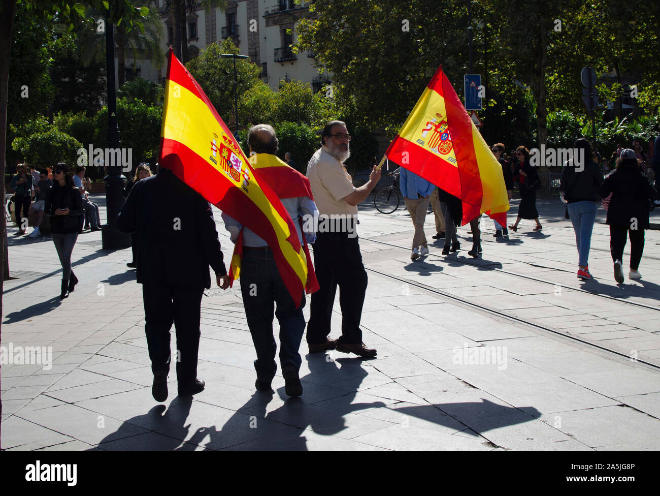 Trois pro-unité hommes tenant le drapeau espagnol dans les rues de Séville. Banque D'Images