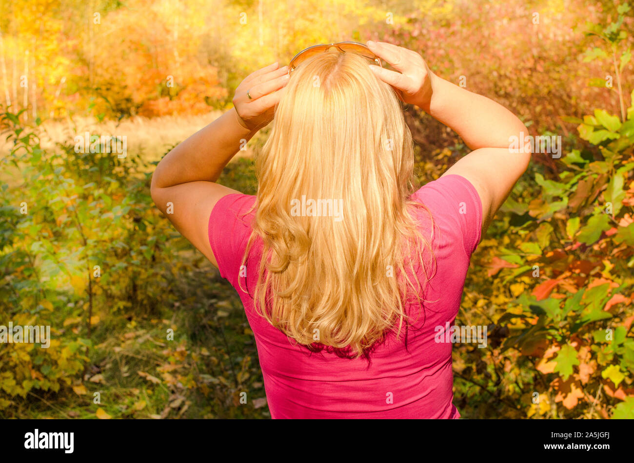 Une jeune femme aux longs cheveux blonds dans la forêt d'automne se détendre dans la nature Banque D'Images