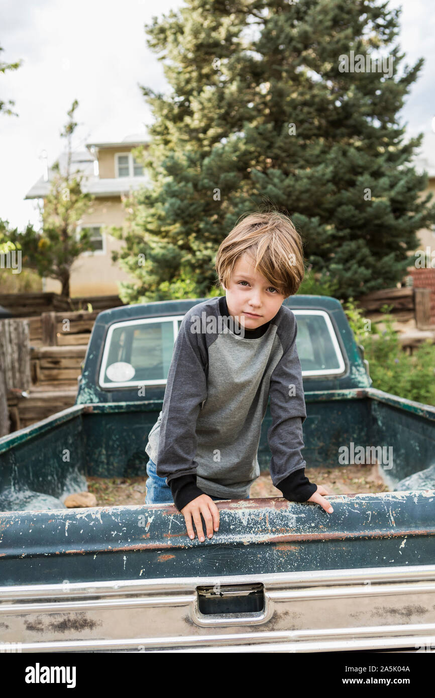 Portrait de 6 ans posant dans le lit d'un vieux pick up truck Banque D'Images