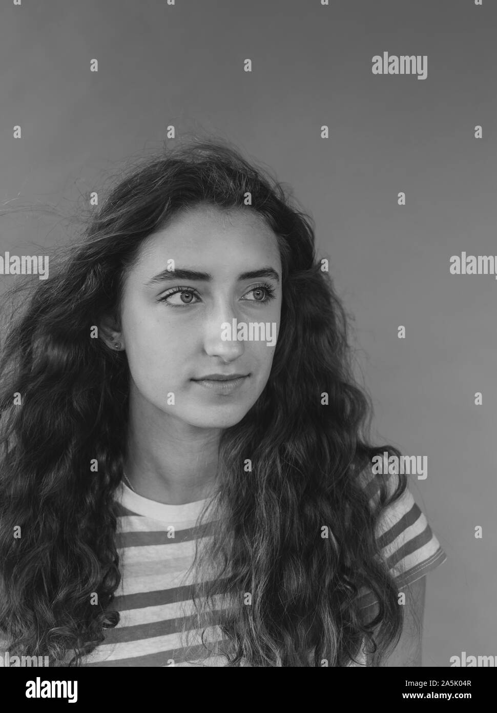 Portrait noir et blanc de la jolie fille de seize ans, le vent souffle à la longue chevelure ondulée Banque D'Images