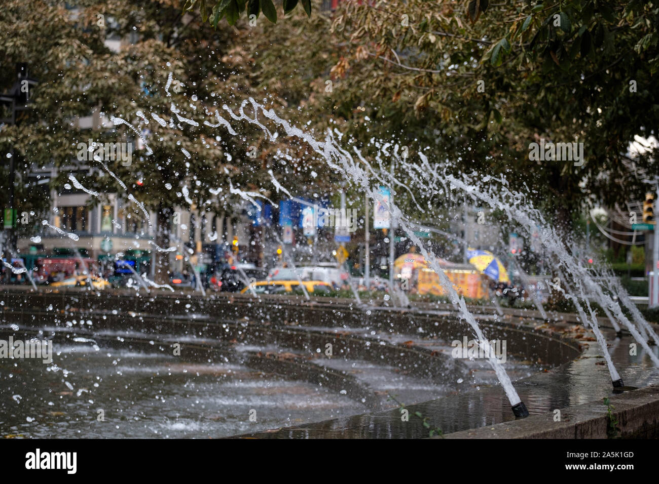 Fontaines pris dans motion avec des arbres d'automne en arrière-plan, juste en dehors de Central Park à New York City Banque D'Images