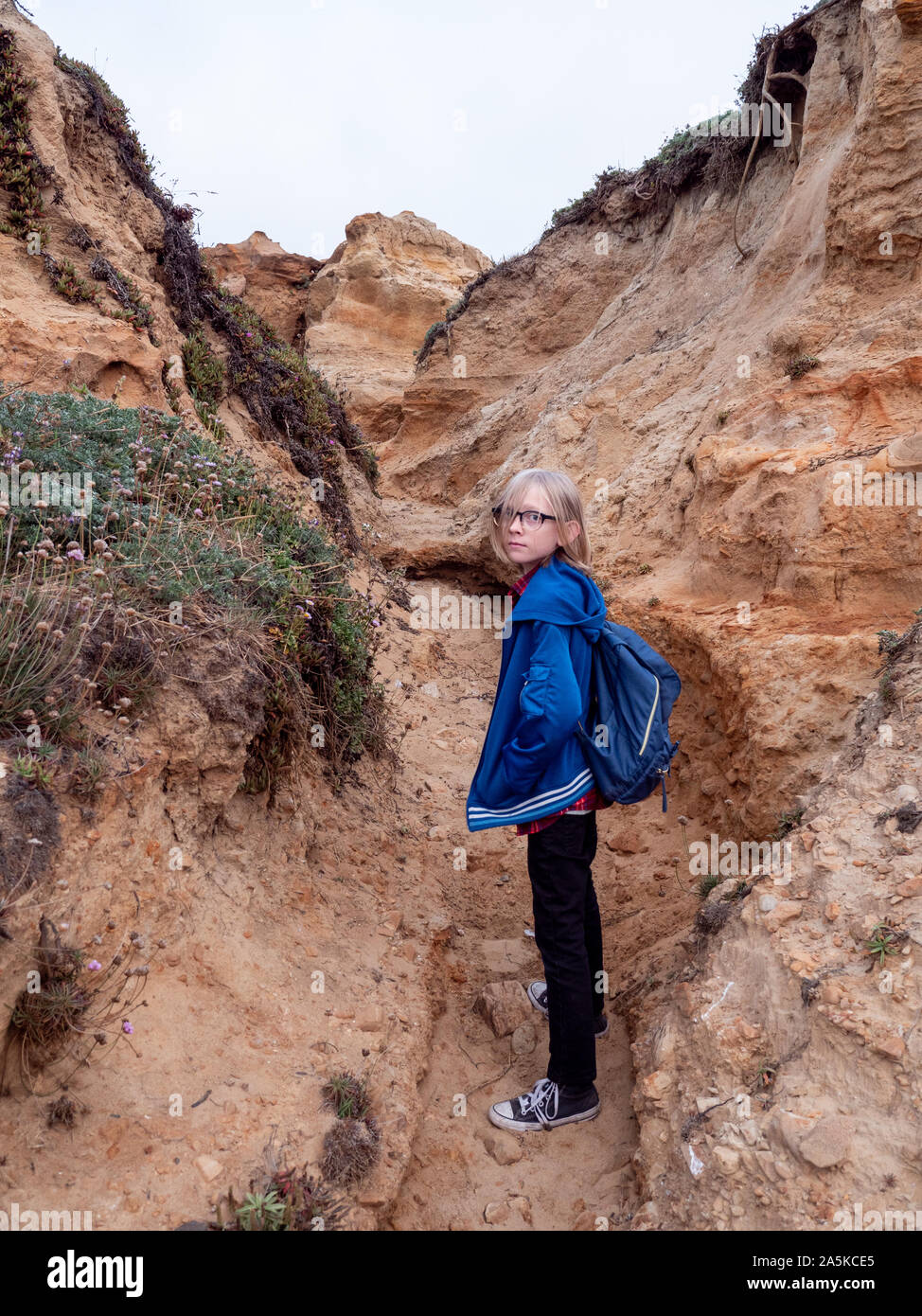 Le Tween garçon à la recherche de retour sur la randonnée à travers les falaises côtières Banque D'Images