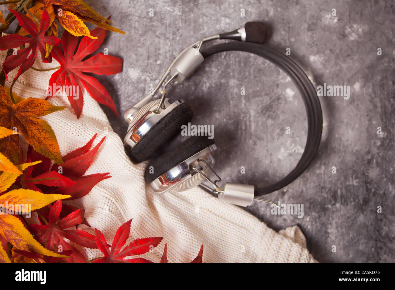 Casque confortable avec l'automne chaud et la musique de plaid tricoté sur le fond gris. Le mode de vie, l'automne, la musique concept. Banque D'Images