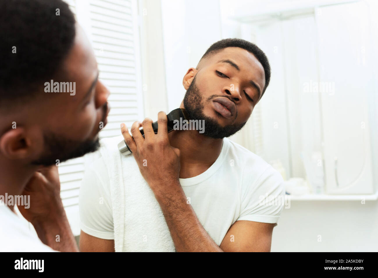 Jeune homme noir à la recherche de miroir et le rasage Tondeuse barbe avec  Photo Stock - Alamy