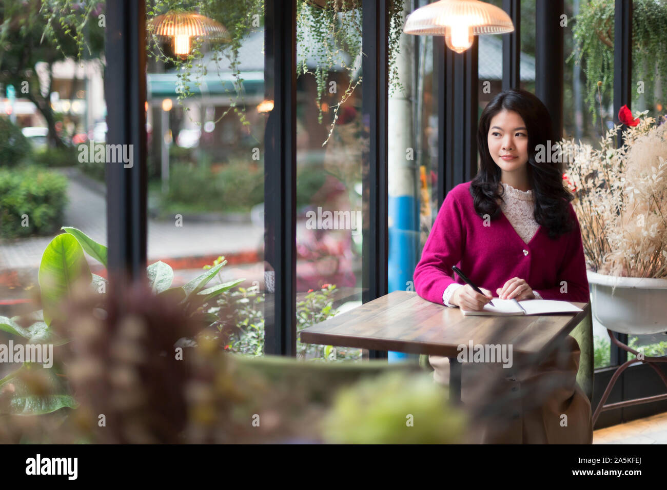 Femme écrit dans le bloc-notes in cafe Banque D'Images