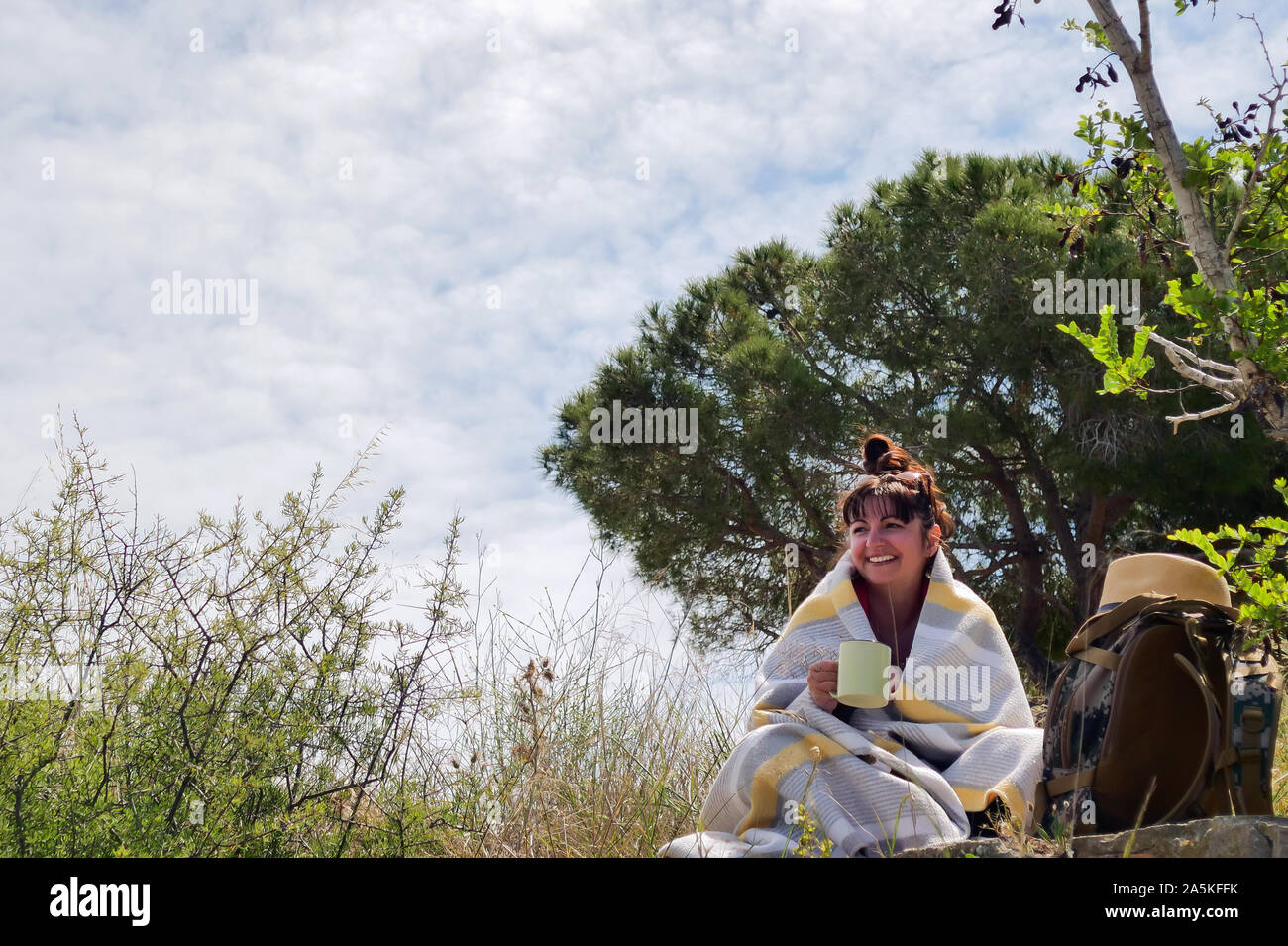 Smiling girl sitting in tourisme nature enveloppé dans une couverture Banque D'Images