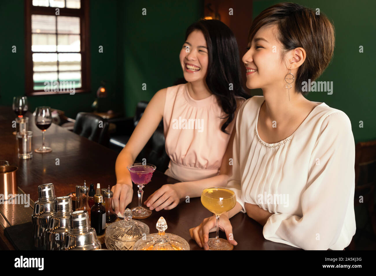 Deux smiling young women enjoying cocktails at bar Banque D'Images
