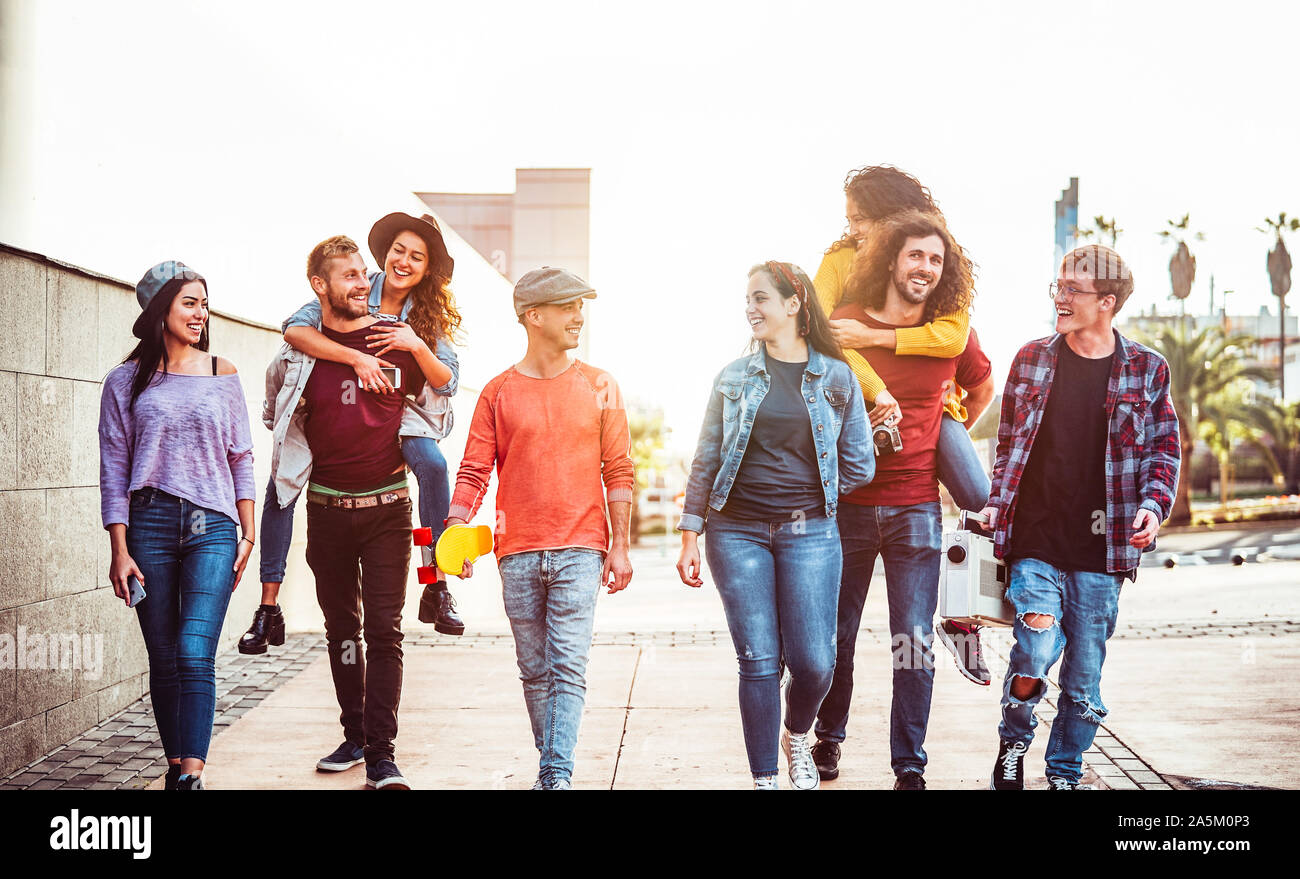 Groupe d'amis heureux de s'amuser en plein air - les jeunes sur le dos en riant et marcher ensemble dans le centre-ville Banque D'Images