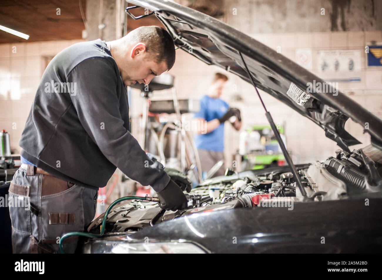 Deux maître mécanicien de voiture auto réparateurs technicien de contrôles et les réparations l'état du moteur sous le capot du véhicule service shop Banque D'Images