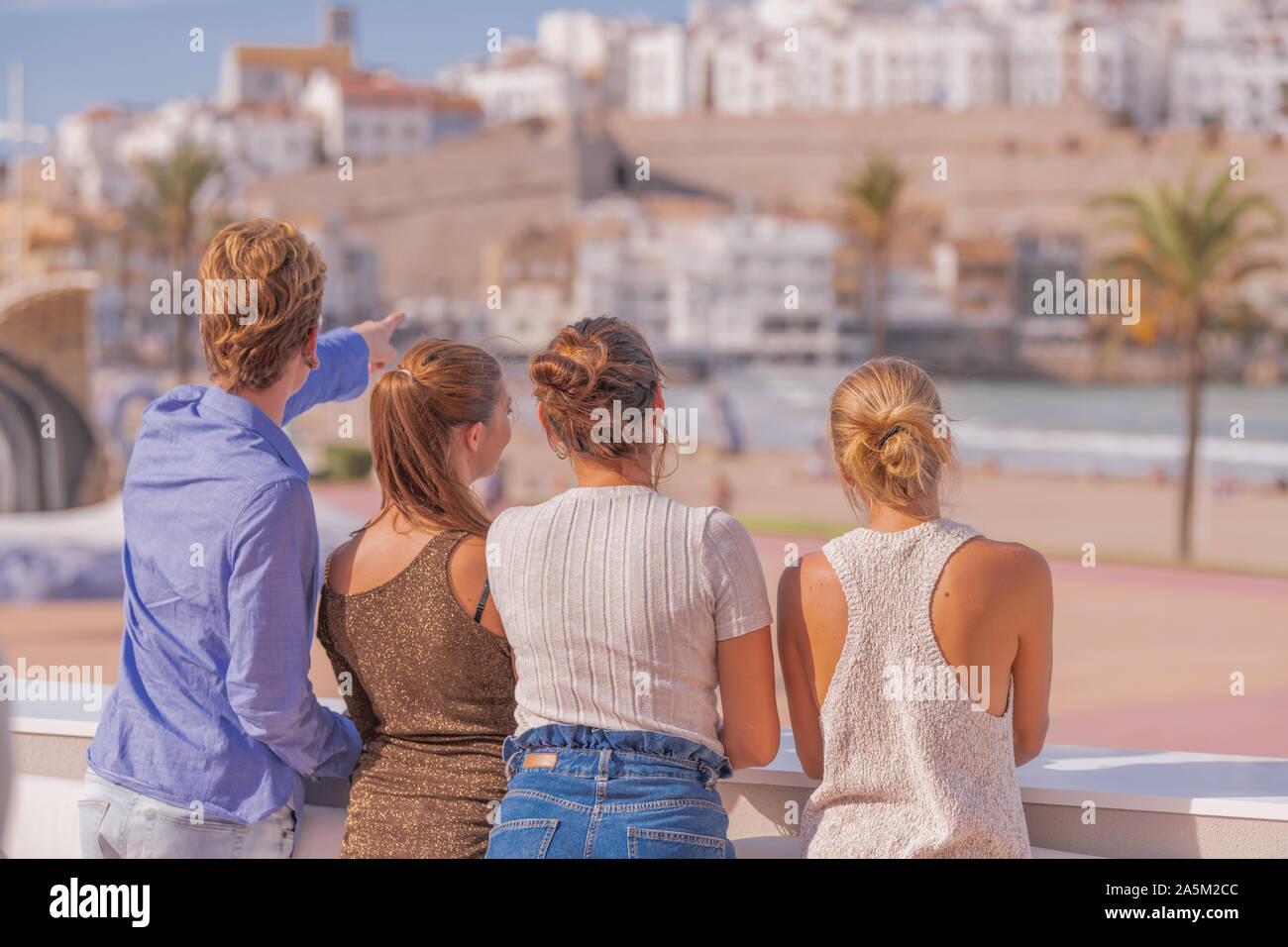 Belles filles debout devant un beau paysage avec le dos de l'appareil accompagné d'un jeune homme aux cheveux blonds qui pointe vers Banque D'Images