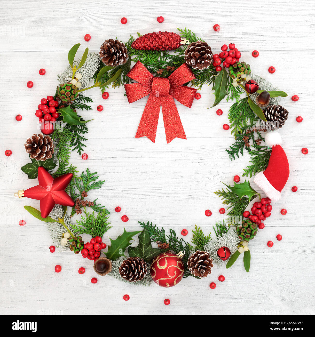 Couronne de Noël avec red bow, décorations babiole, flore hiver et lâche des baies de houx sur fond de bois rustique. Banque D'Images