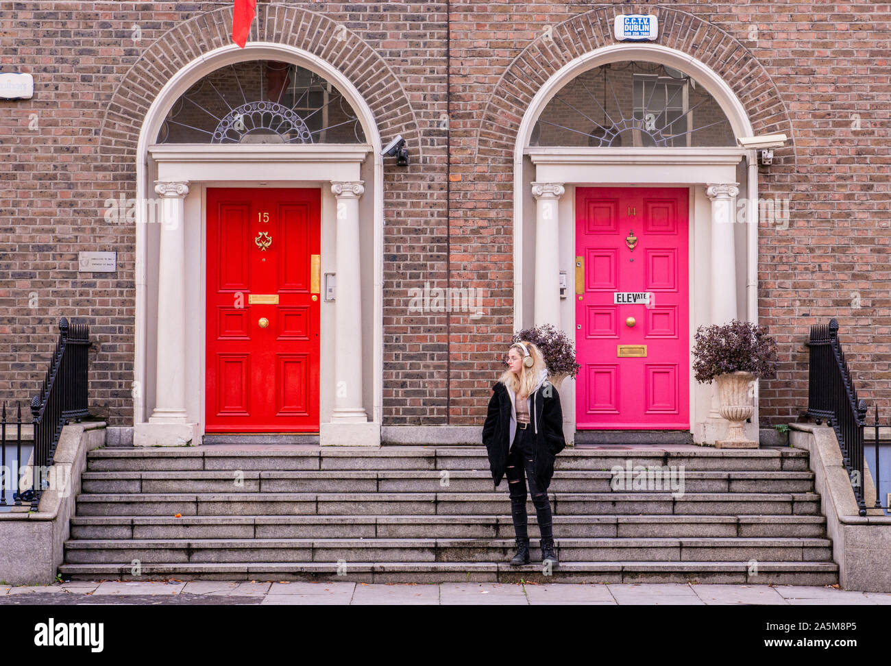 Jeune femme sur l'escalier en face de bâtiment résidentiel, Dublin, Irlande Banque D'Images