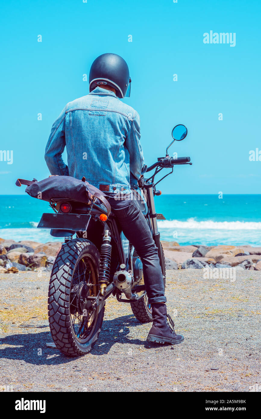 Une personne assise sur la moto tout en regardant l'océan Photo Stock -  Alamy