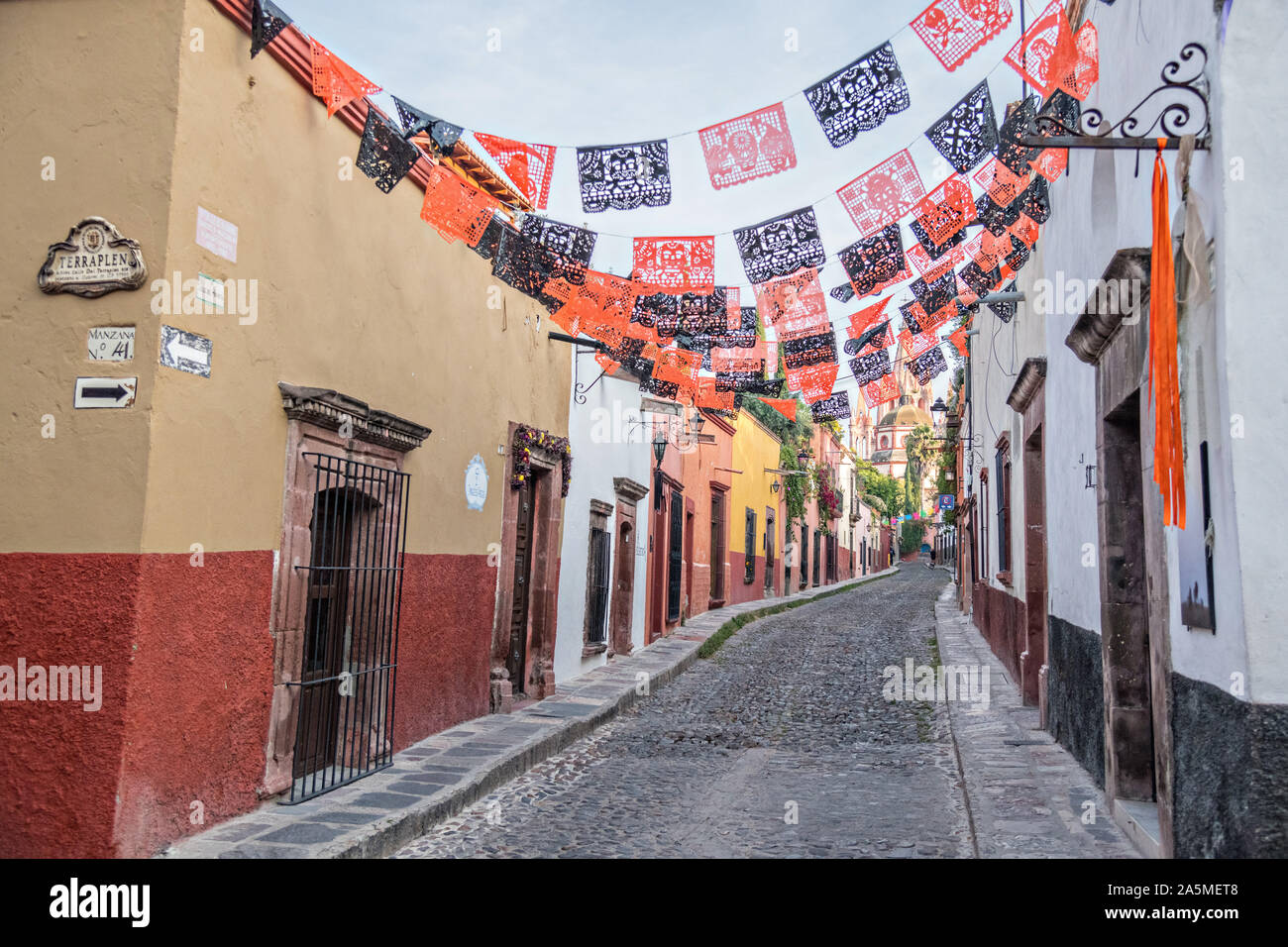 Les dômes et les clochers de la Parroquia San Miguel Arcangel church vu à travers des banderoles de papier appelé papel picado enfilés pour célébrer le Jour de la fête des morts sur Aldama Street dans le quartier historique de San Miguel de Allende, Mexique. Banque D'Images