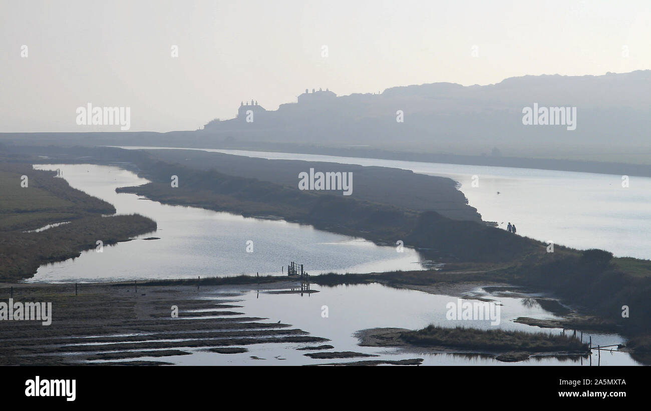 L'estuaire de la rivière Cuckmere sur la côte sud de l'Angleterre. La silhouette sont les vieux cottages garde-côtes par la mer. Un matin d'hiver brumeux. Banque D'Images