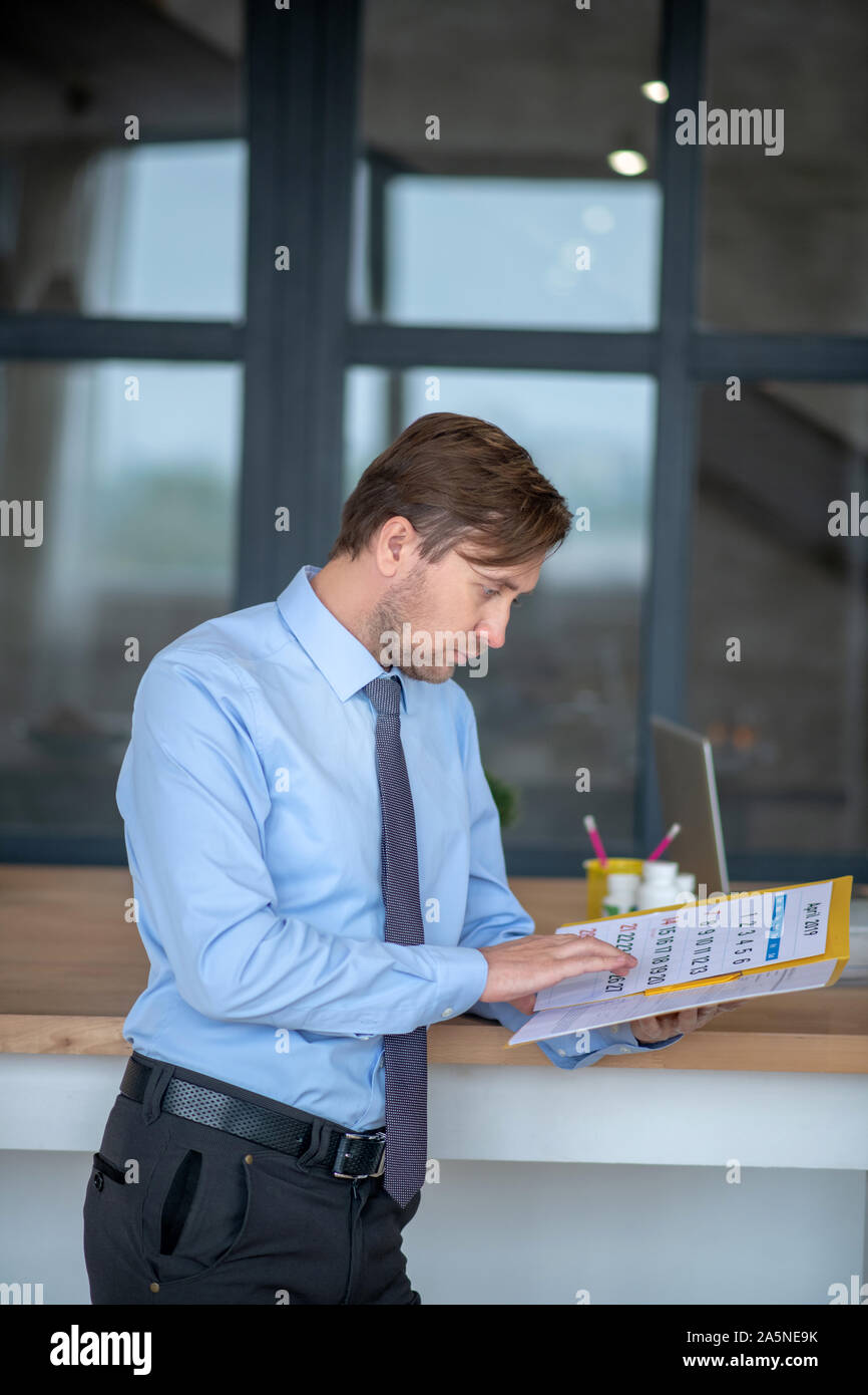 Dark-haired young handsome businessman checking le calendrier Banque D'Images