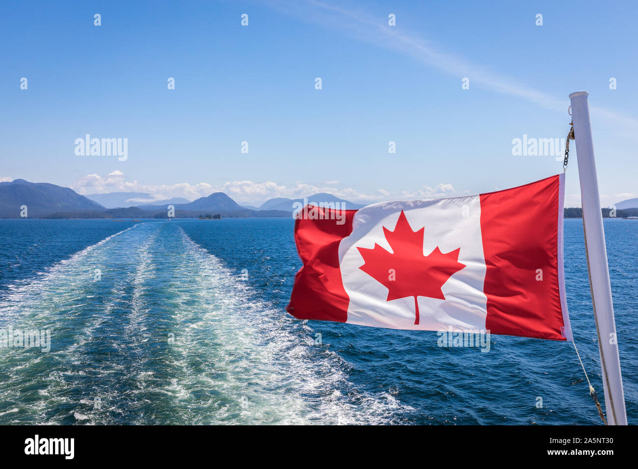 Un gros plan du drapeau canadien au vent à l'arrière du ferry alors que le bateau fait route à travers le passage de l'intérieur, Colombie-Britannique, Canada Banque D'Images
