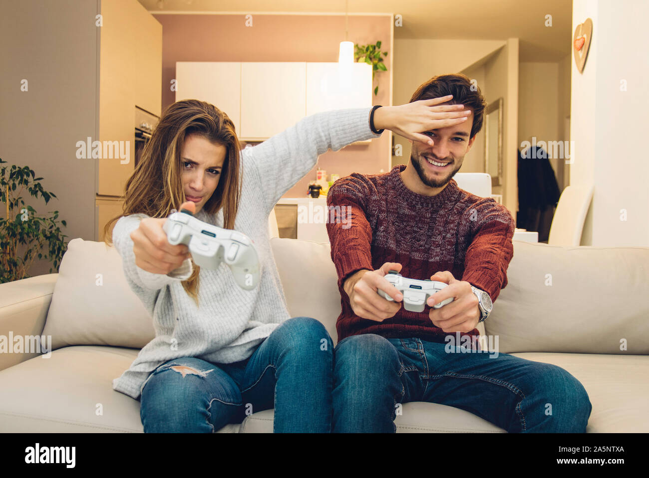 Jeune couple ayant l'amusement jouer le jeu vidéo à la maison. Banque D'Images