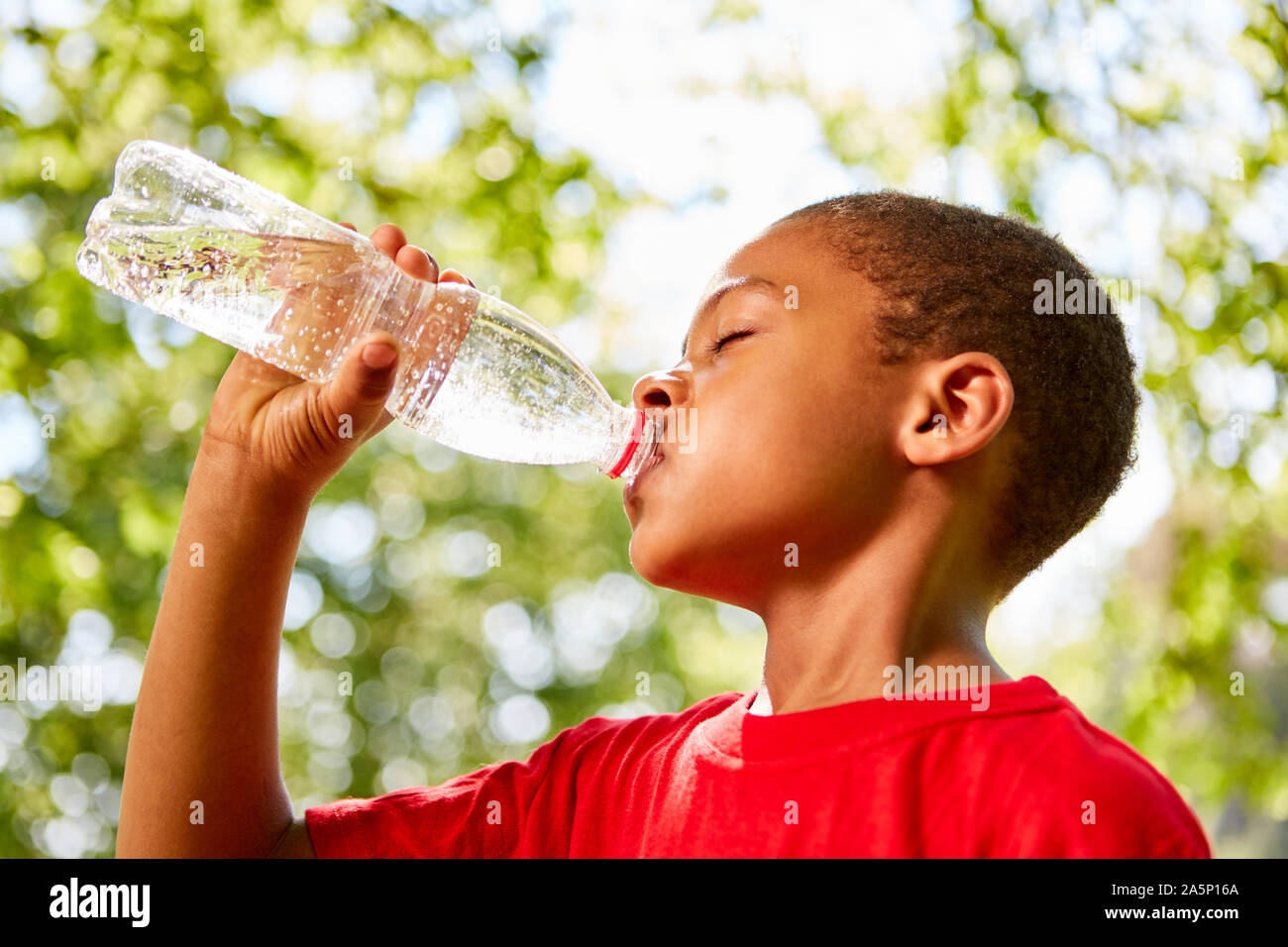 African boy est assoiffé nous réjouissons de boire une bouteille d'eau Banque D'Images