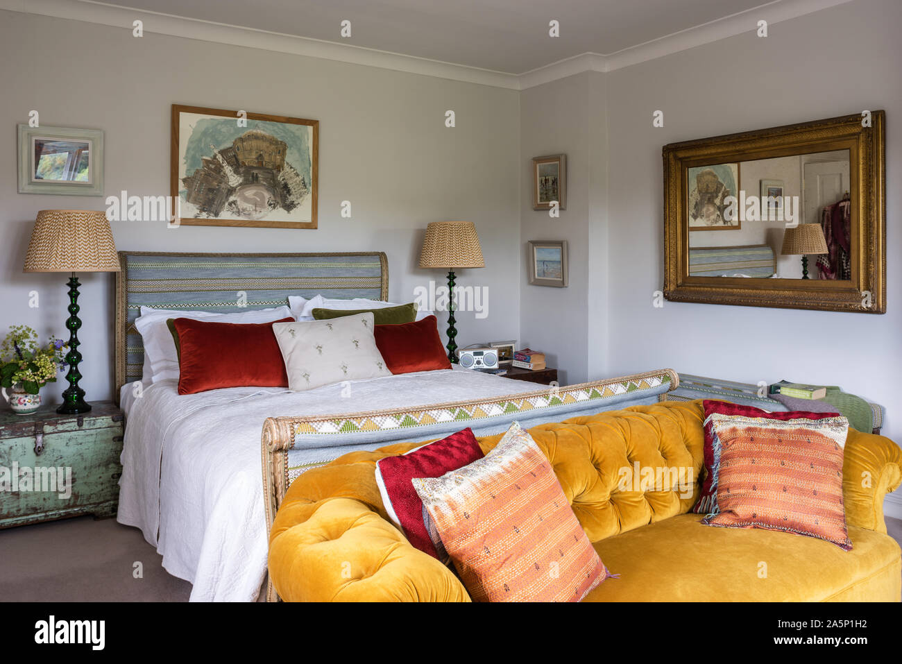 Coussins sur Chesterfield en velours avec un lit double et d''un miroir. Les murs de Farrow & Balls' Ammonite. Banque D'Images