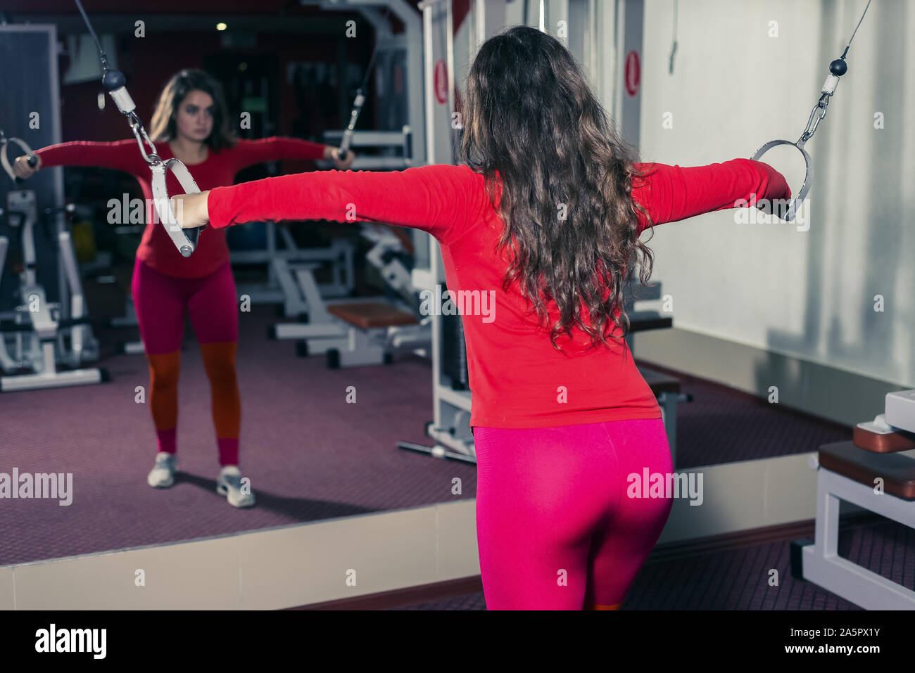 Athletic Girl engagés dans la salle de sport sur le simulateur. remise en forme sports et l'haltérophilie. femme cherche dans le reflet du miroir Banque D'Images