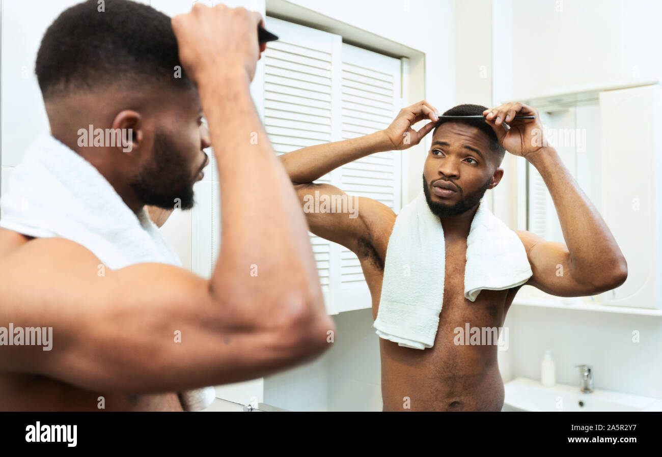 Awesome african american guy peignant ses cheveux à la salle de bains Banque D'Images