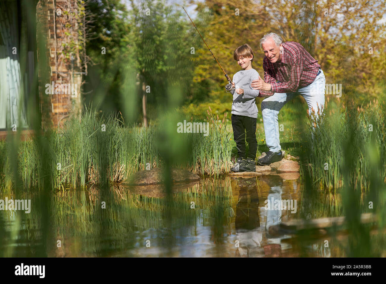 Grand-père et petit-fils s'amuser pêche ensemble par le lac en été Banque D'Images