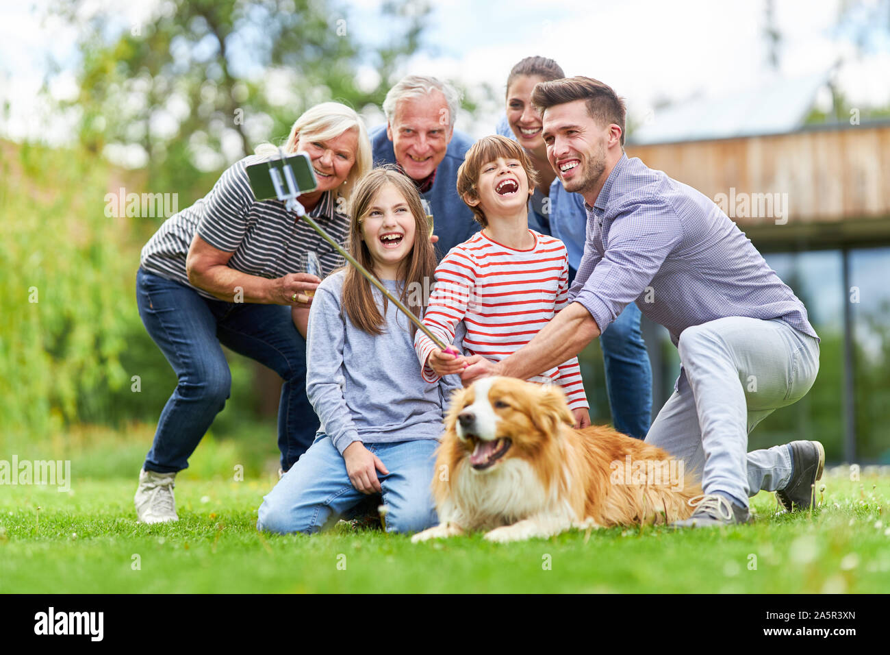 Trois Génération de la famille de prendre une dans le jardin avec Selfies avec chien Stick Selfies Banque D'Images
