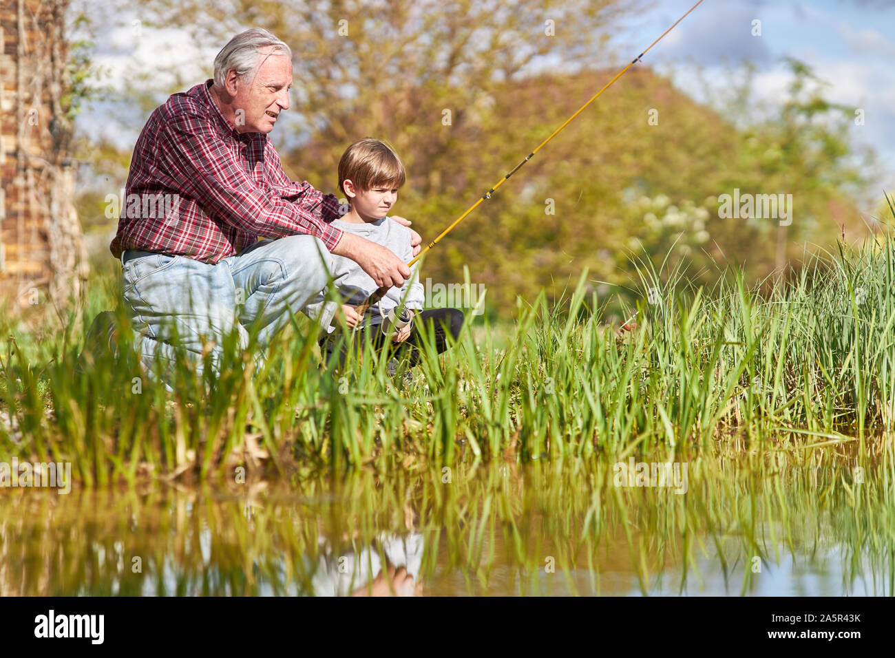Grand-père et petit-fils de la pêche sur le lac en pleine nature pour la patience et les loisirs Banque D'Images