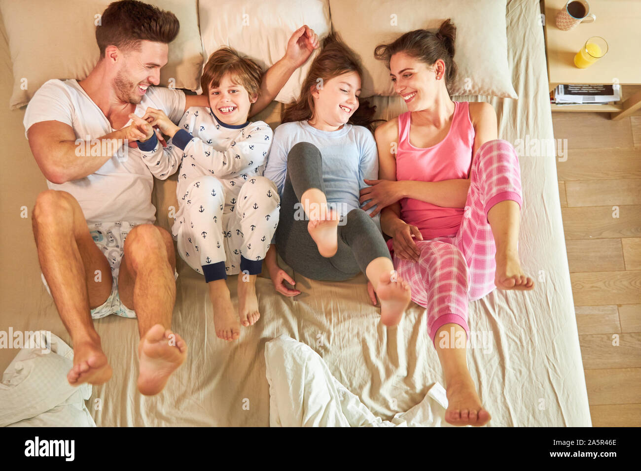 Famille avec deux enfants est heureusement kidding autour dans le lit dans la chambre à coucher Banque D'Images