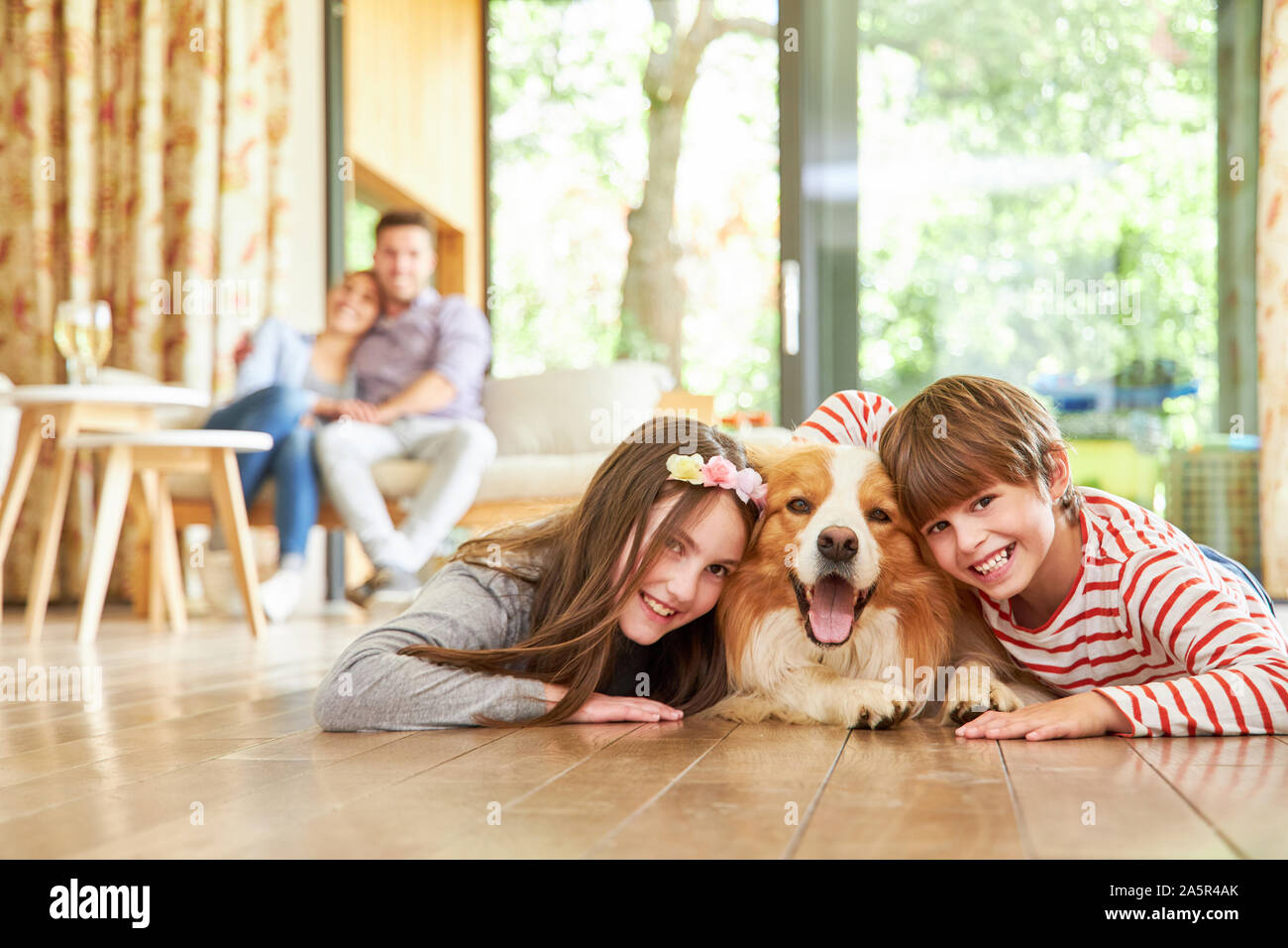 Deux enfants joyeux caresser avec leur chien sur le salon plancher Banque D'Images