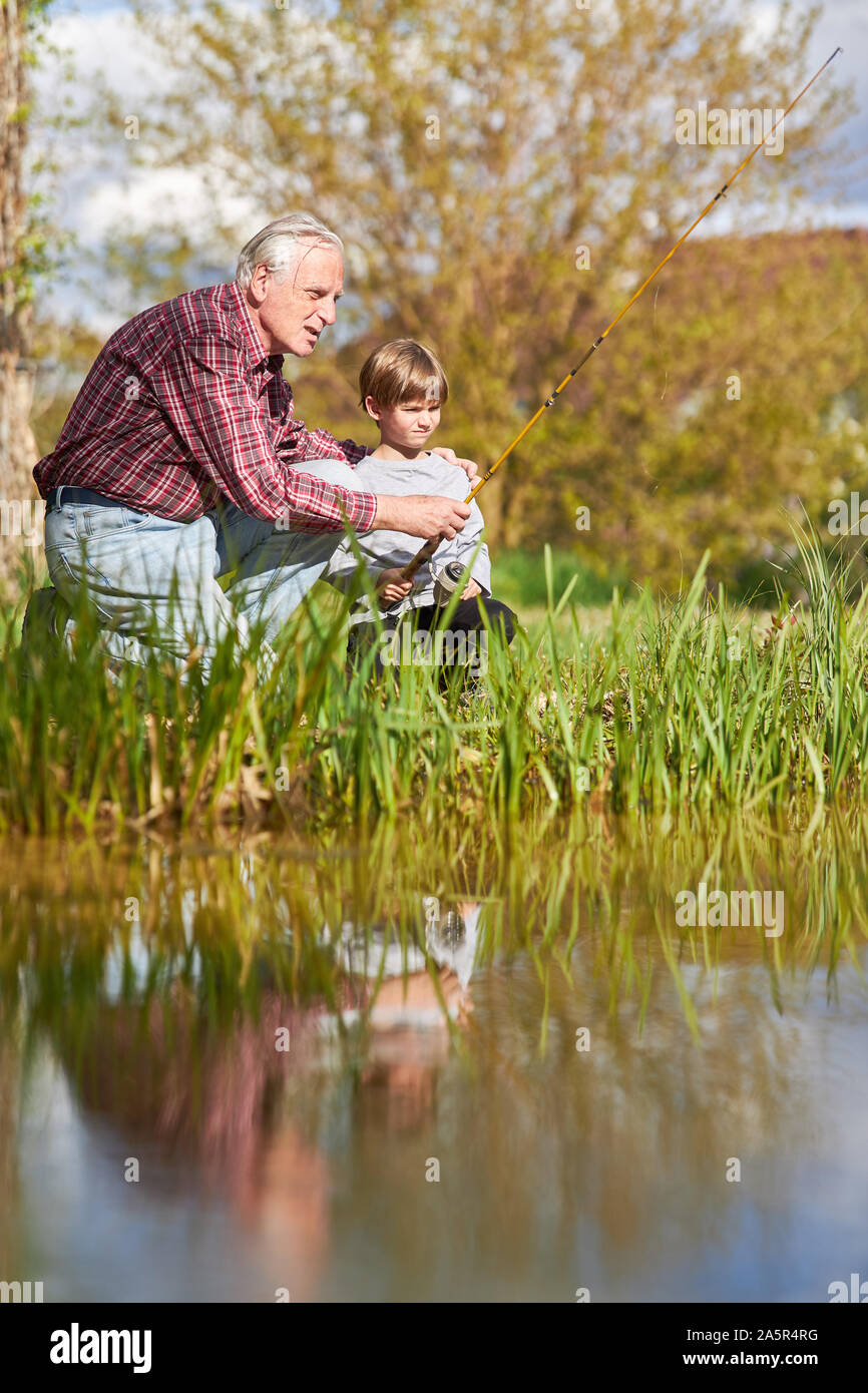 Grandpa montre et explique son petit-fils de la pêche sur le lac en été Banque D'Images