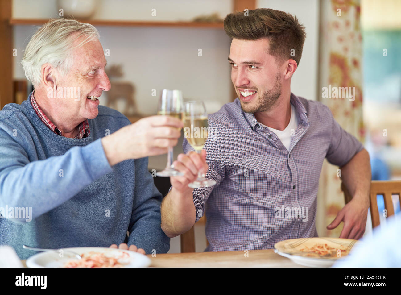 Ronflement Senior champagne avec son fils à une fête familiale Banque D'Images