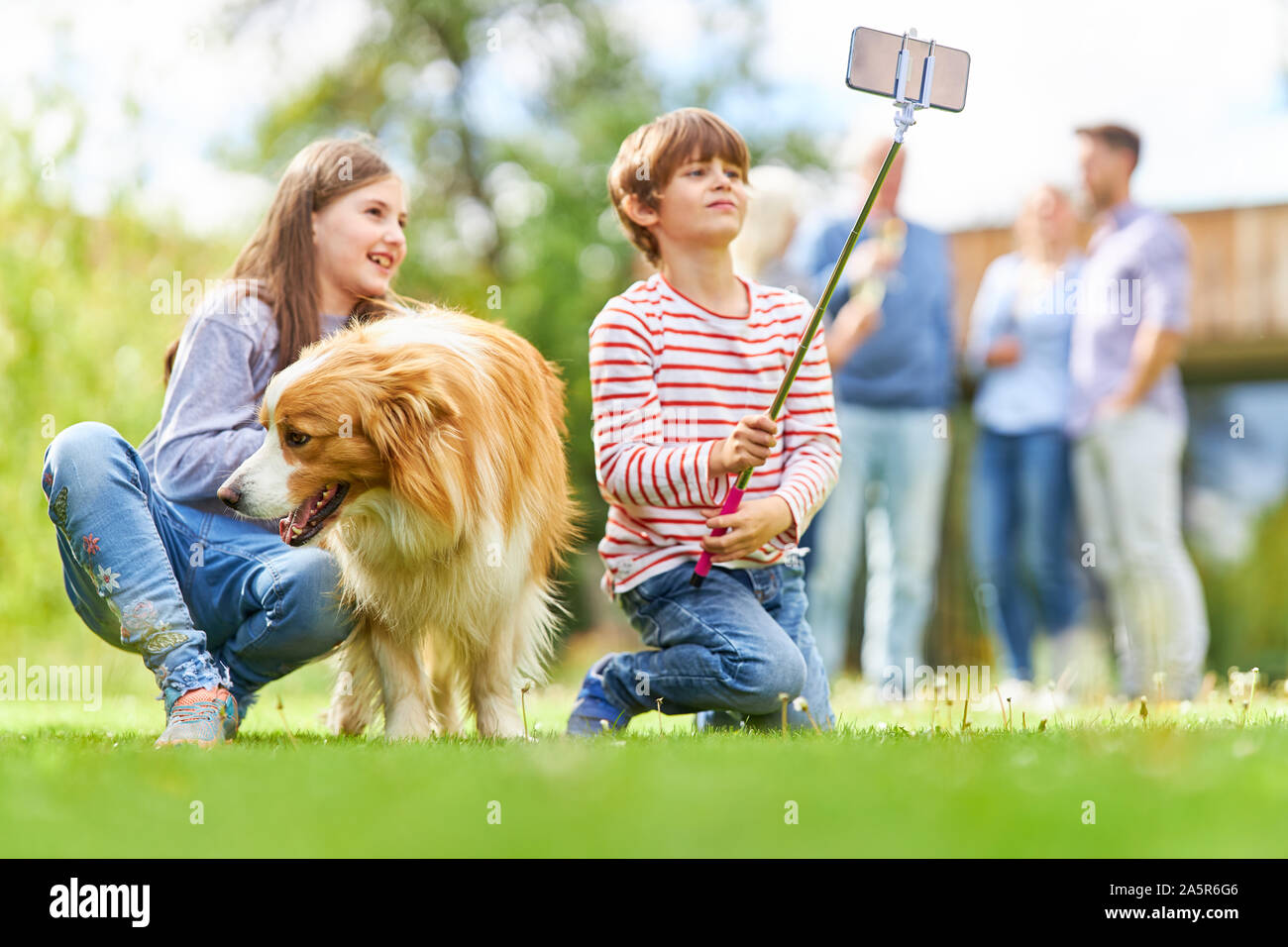 Les enfants des frères et sœurs avec chien prendre un smartphone avec selfies sur stick selfies Banque D'Images