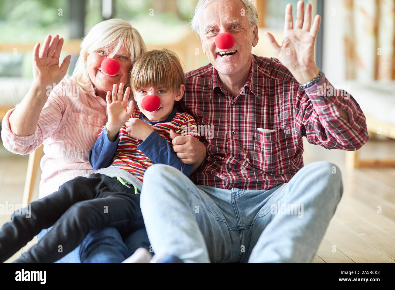 Les grands-parents célébrer carnaval avec petit-enfant déguisé en clown avec un nez rouge Banque D'Images