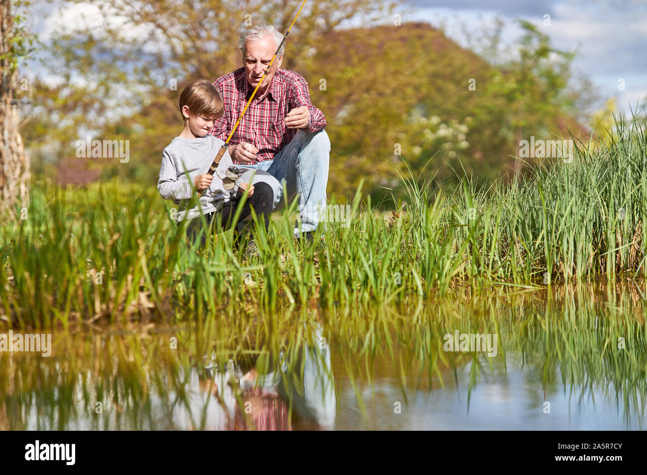 Grand-père et petit-fils ensemble pendant que la pêche par le lac en été dans la nature Banque D'Images