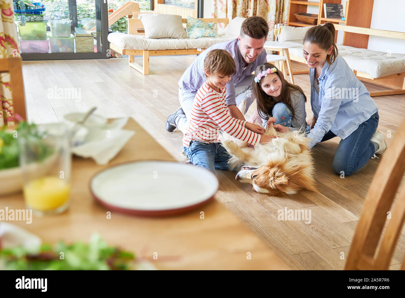 Famille heureuse et deux enfants jouent avec le chien dans le salon Banque D'Images