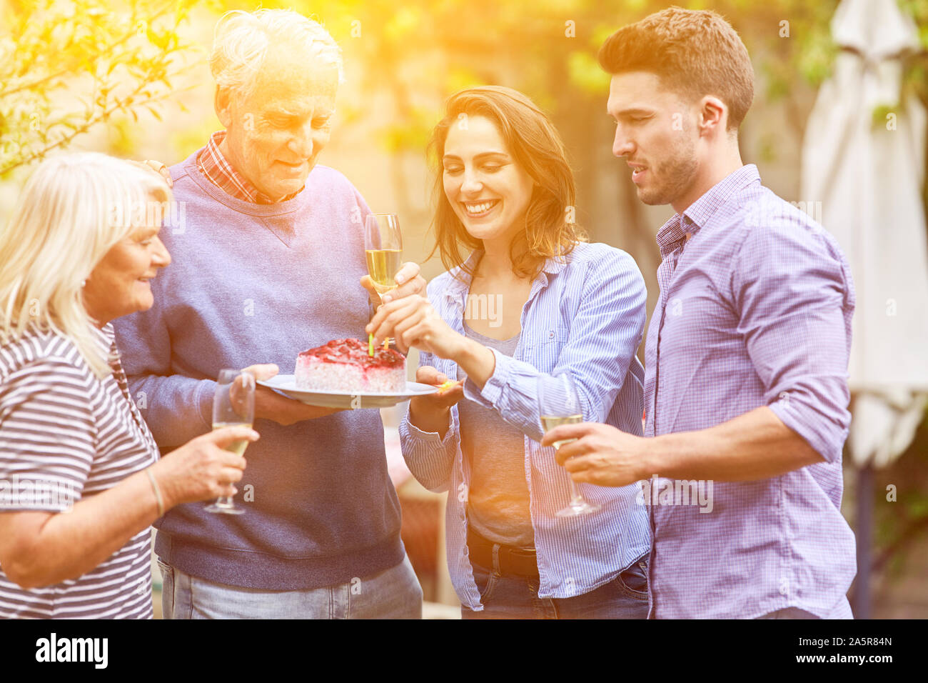 Famille à la fête d'anniversaire dans le jardin avec du gâteau et du champagne en été Banque D'Images