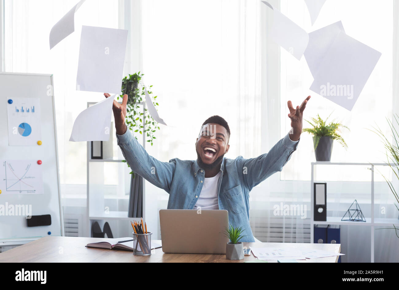 Black Businessman Throwing Papers joyeux dans l'air sur le lieu de travail Banque D'Images
