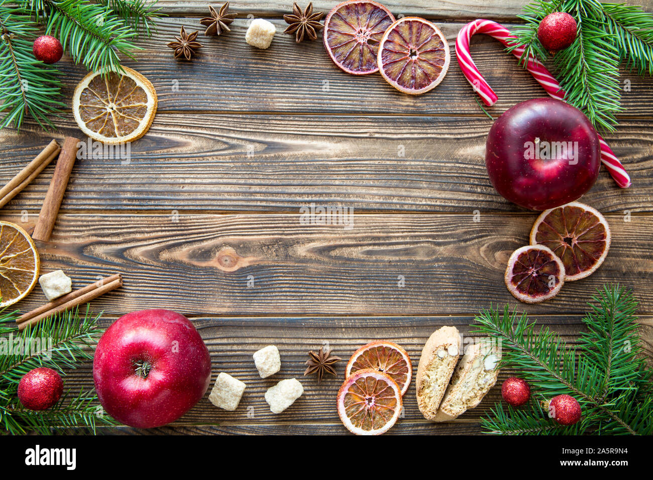 Savoureux de Noël arrière-plan. L'espace pour texte, copiez l'espace. Pommes rouges, des bonbons de Noël lumineux stick, épices traditionnelles et les cookies sur table en bois brun Banque D'Images