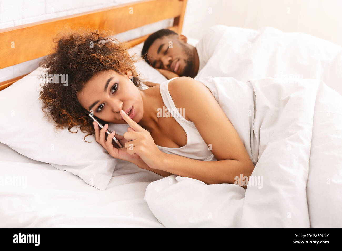 Femme noire cheater parler en privé on cellphone in family bed Banque D'Images