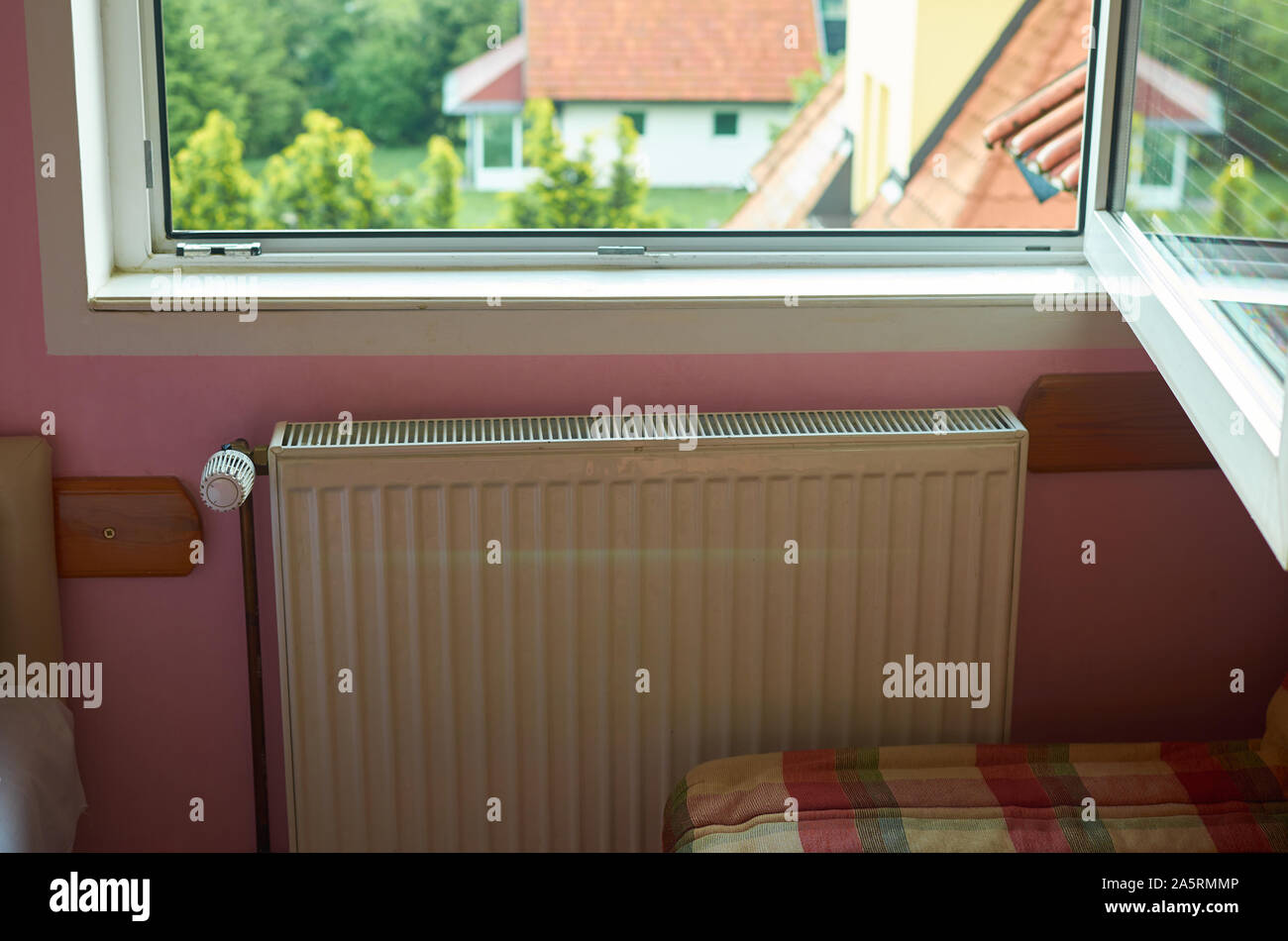 Le radiateur de chauffage dans une chambre avec un détail de toits rouges à  travers une fenêtre ouverte Photo Stock - Alamy