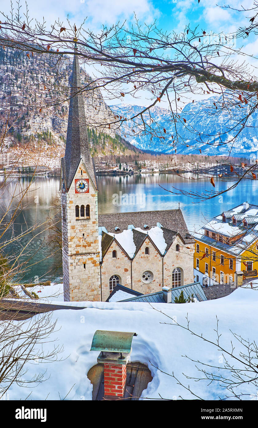 Vieille ville à pied avec vue sur la construction de l'Église évangélique, vu à travers les branches des arbres et les toits enneigés de Halltatt, Salzkammergut, Autriche Banque D'Images