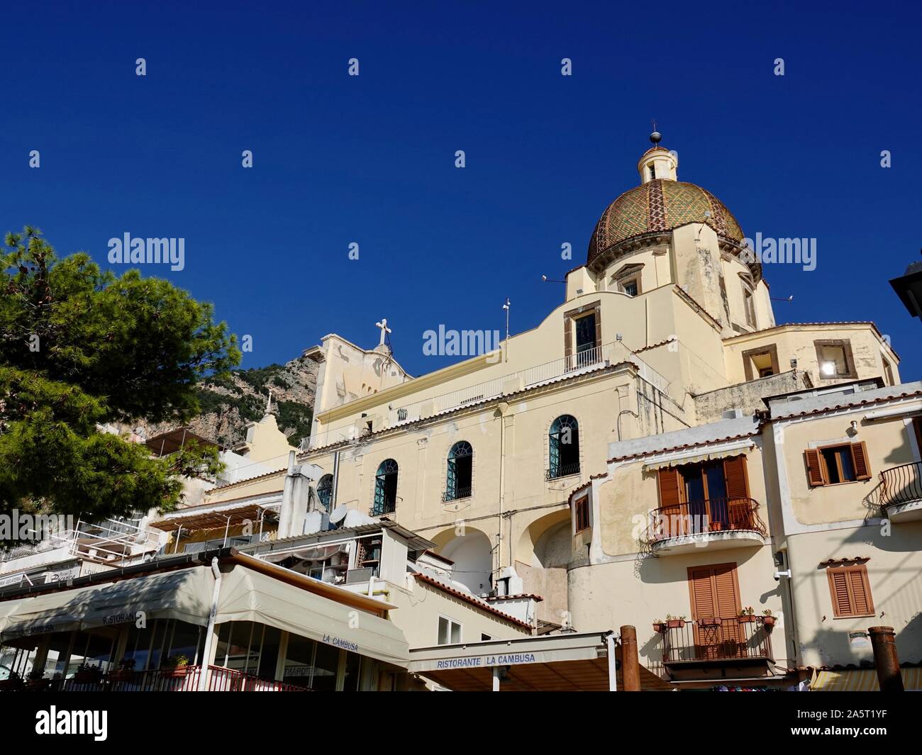 Dôme de l'Église de Saint Marie de l'Assomption, Santa Maria Assunta, s'élevant au-dessus de la ville et le restaurant la Cambusa, Positano, Italie. Banque D'Images