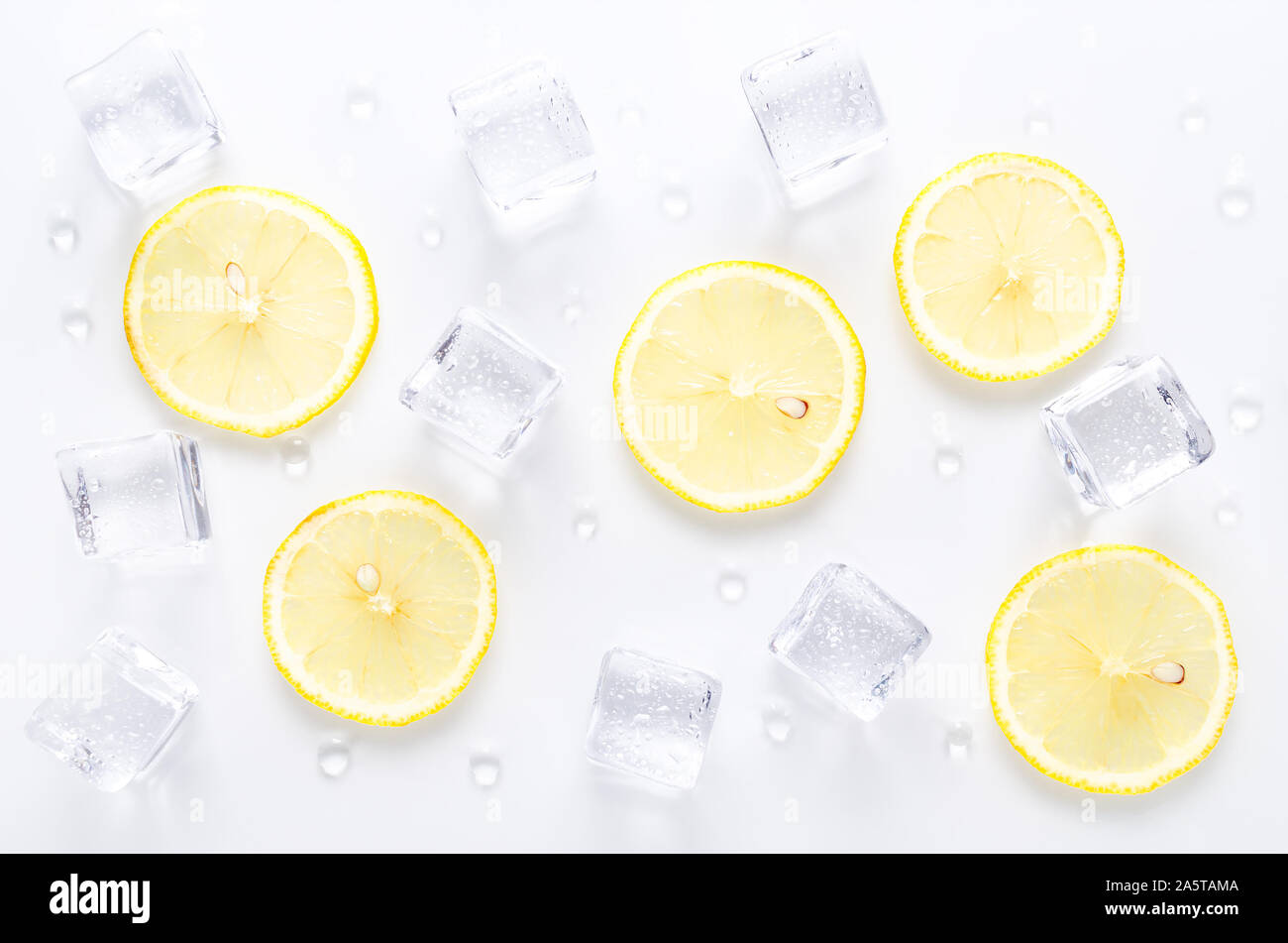 Des cubes de glace et de tranche de citron frais avec de l'eau gouttes sur fond blanc Banque D'Images