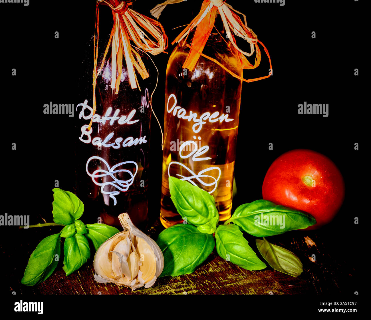 Vinaigre balsamique et huile d'orange Date de concert avec des ingrédients frais comme le basilic, l'ail et la tomate. Banque D'Images