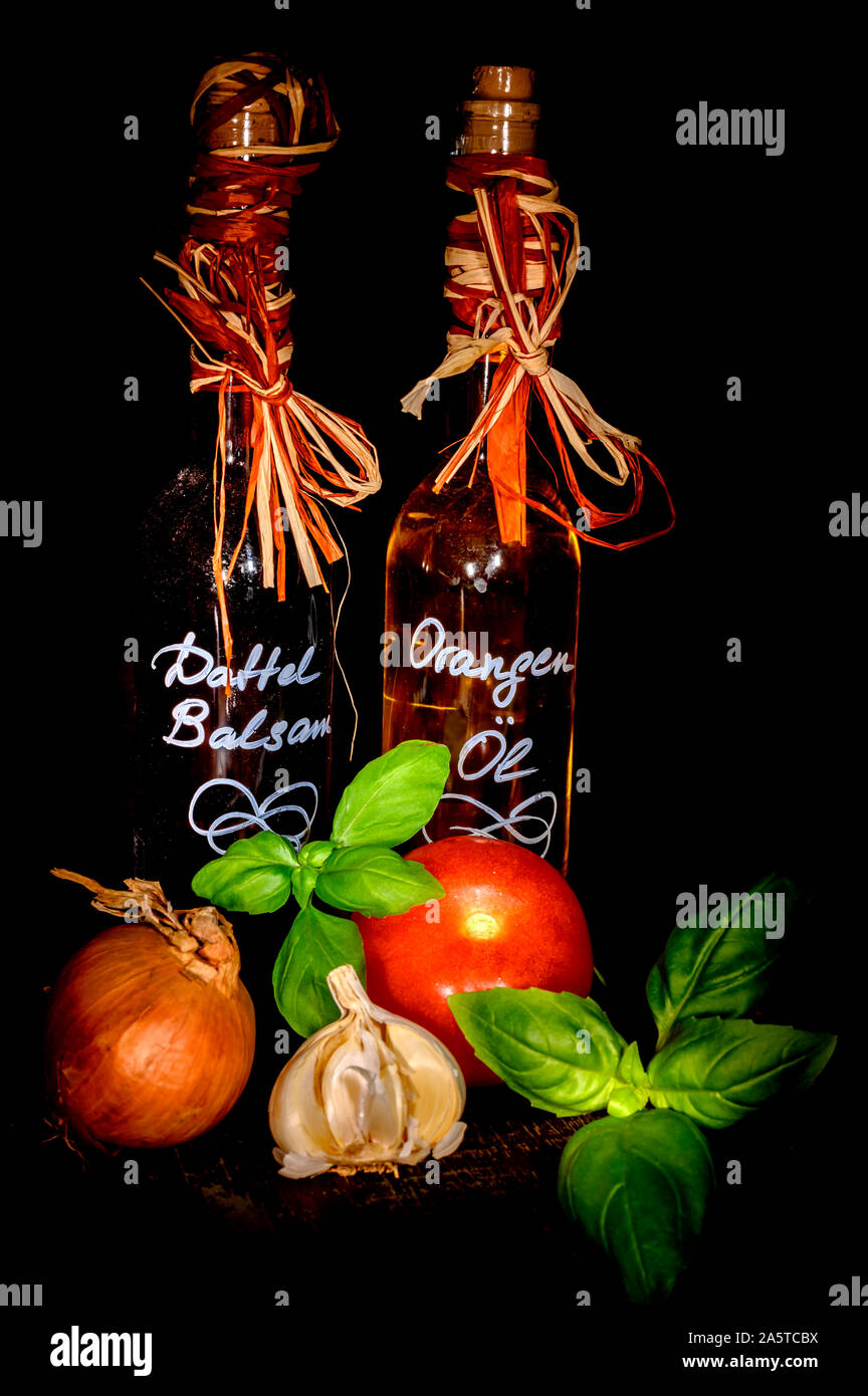 Vinaigre balsamique et huile d'orange Date de concert avec des ingrédients frais comme le basilic, l'ail et la tomate. Banque D'Images