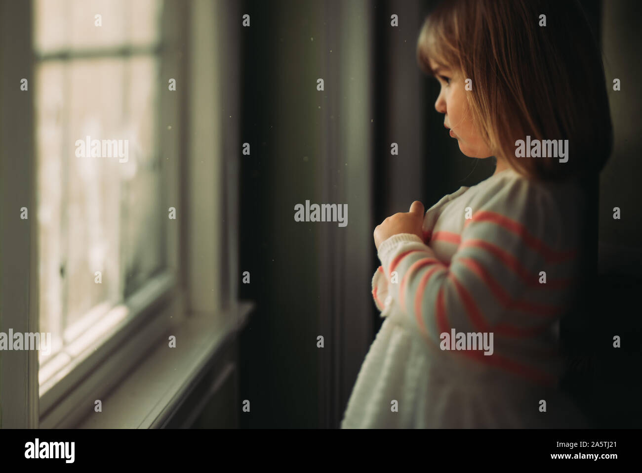 Girl looking out window boutonnant sweater Banque D'Images