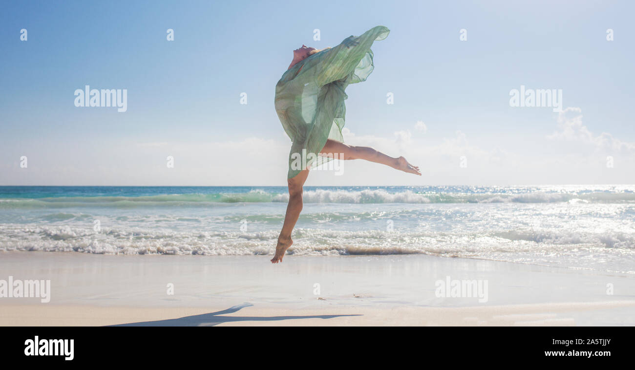 Femme sautant sur la plage comme un oiseau Banque D'Images