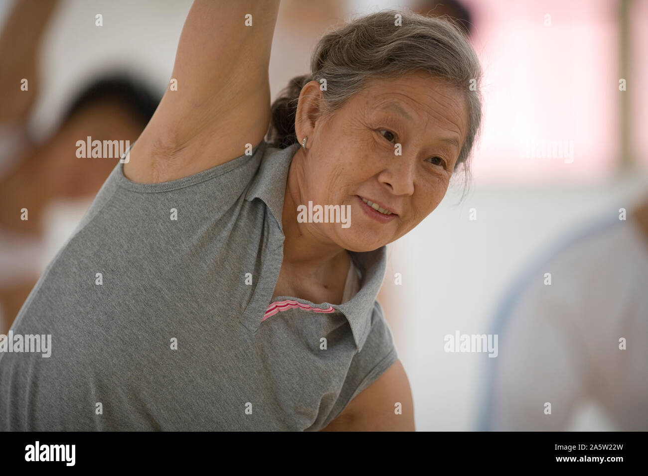 Senior woman doing yoga pose avec un groupe de femmes dans une classe. Banque D'Images